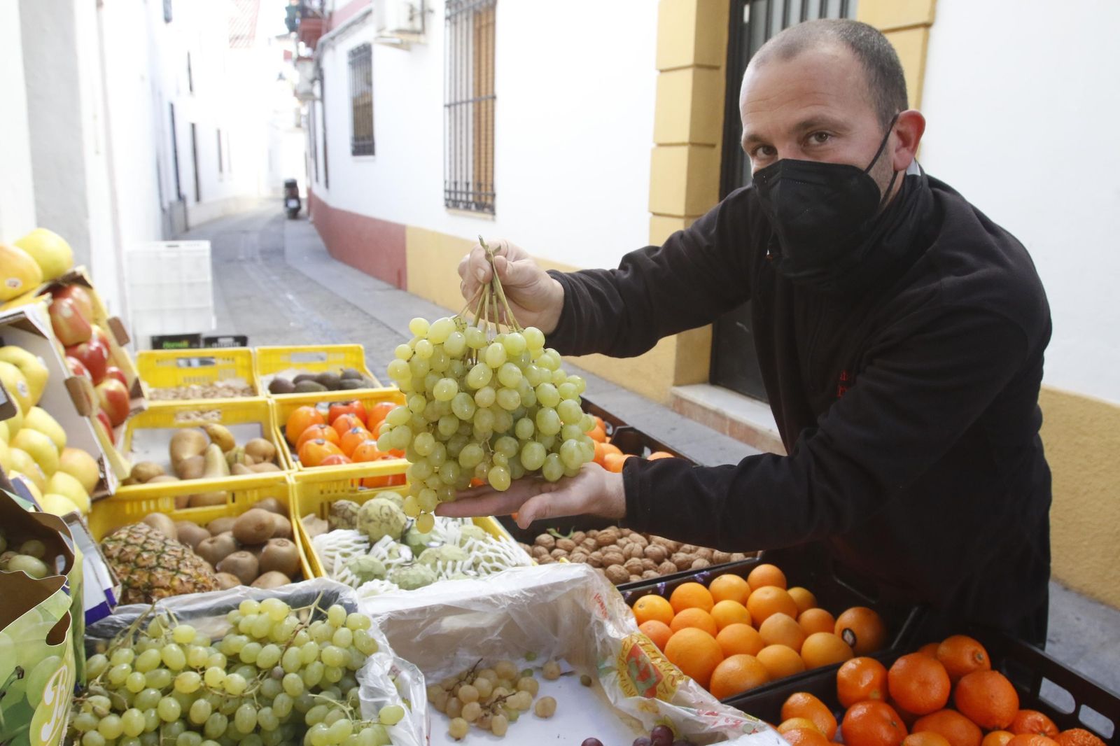 Javier, de la frutería Casa Francisco, sostiene unos racimos de uvas para esta Nochevieja.