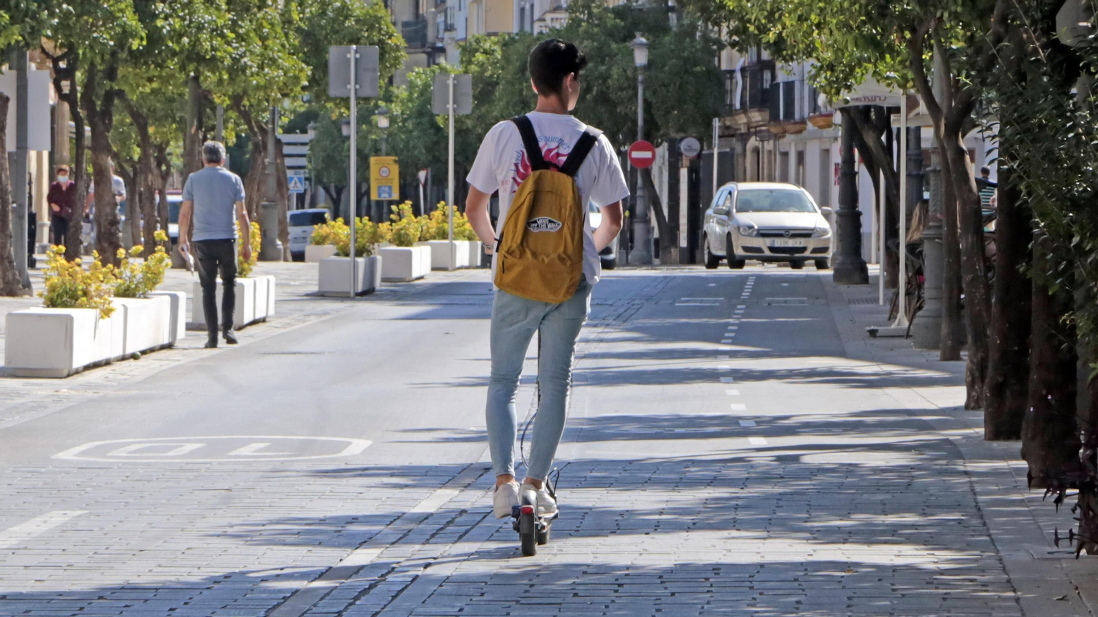 Un joven circulando con su patinete eléctrico por el carril bici.