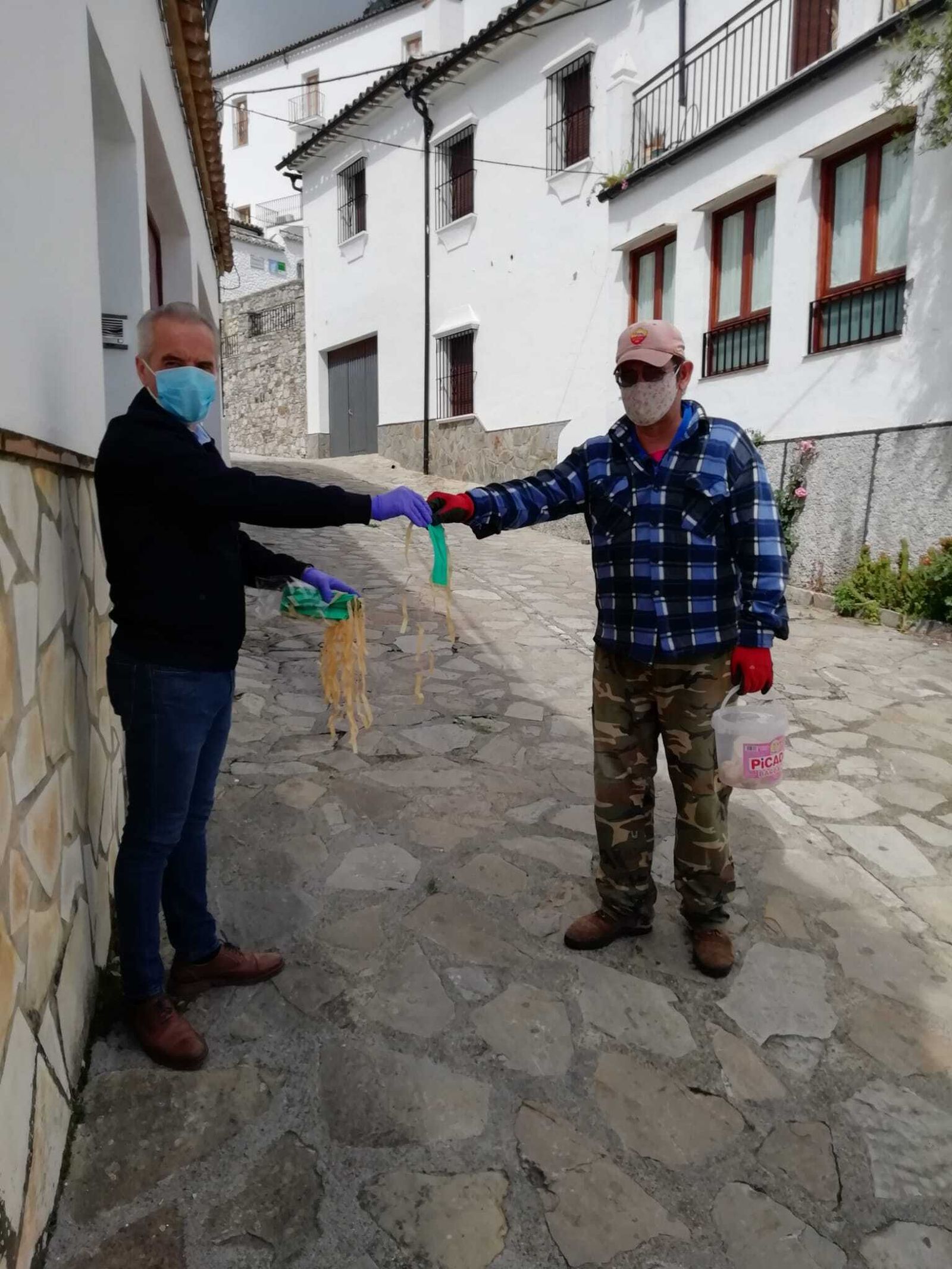 El alcalde de Villaluenga del Rosario, Alfonso Moscoso, entrega una mascarilla a un vecino de la localidad.