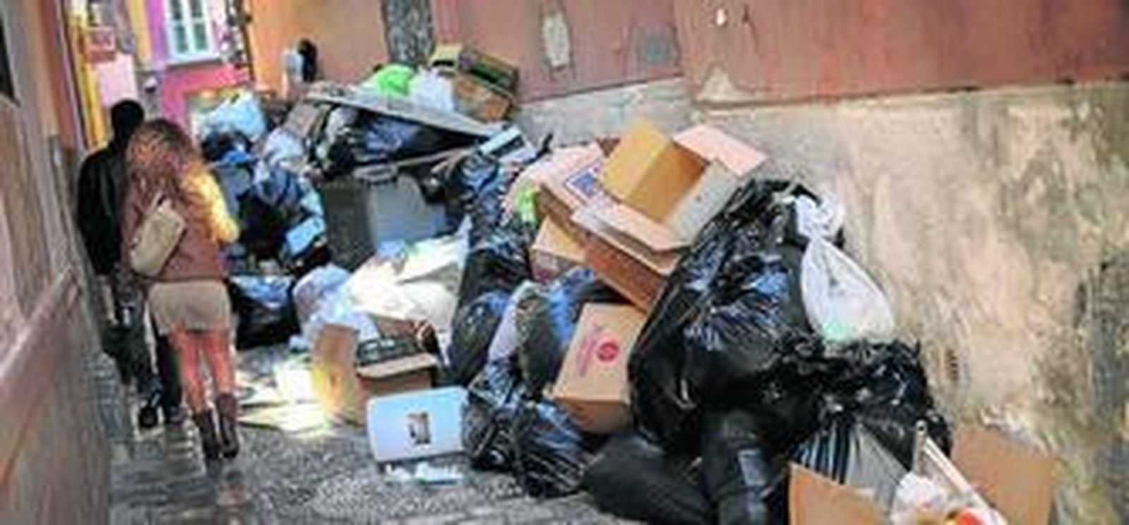 Una pareja 'pasa' al lado de las bolsas de basura en la calle Fresca.