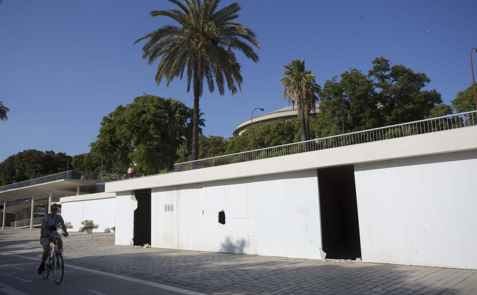 Un ciclista pasa ante el edificio ubicado junto a la Torre del Oro, que tiene dos aberturas del tamaño de una puerta.