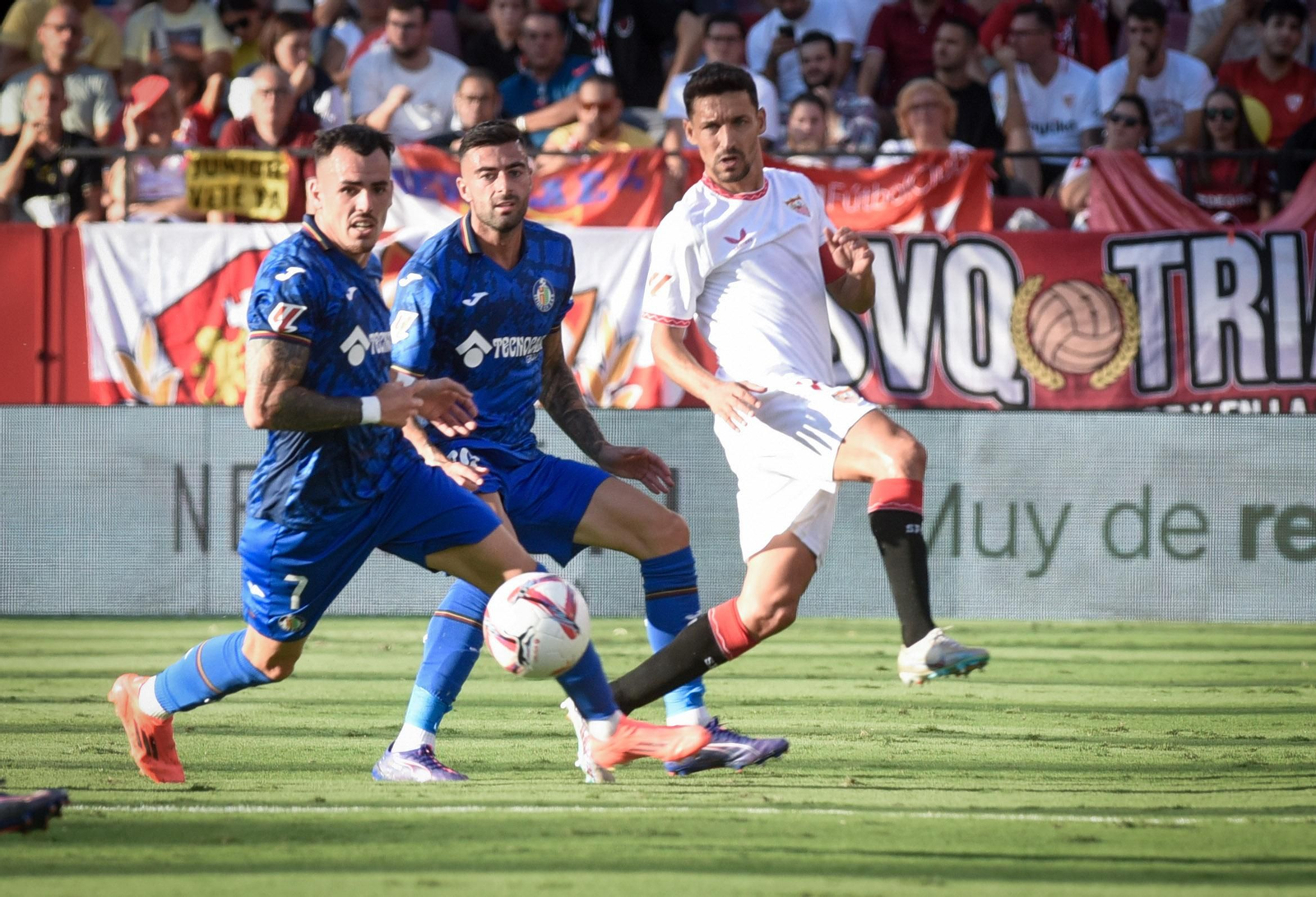 Jesús Navas mete un balón entre dos rivales.
