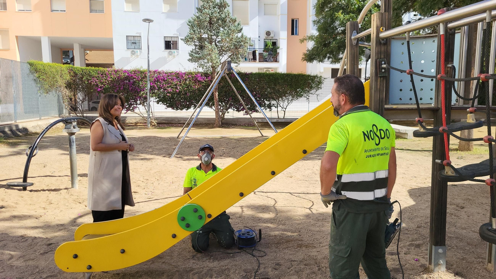 La delegada Evelia Rincón observa el trabajo de reparación de un parque infantil