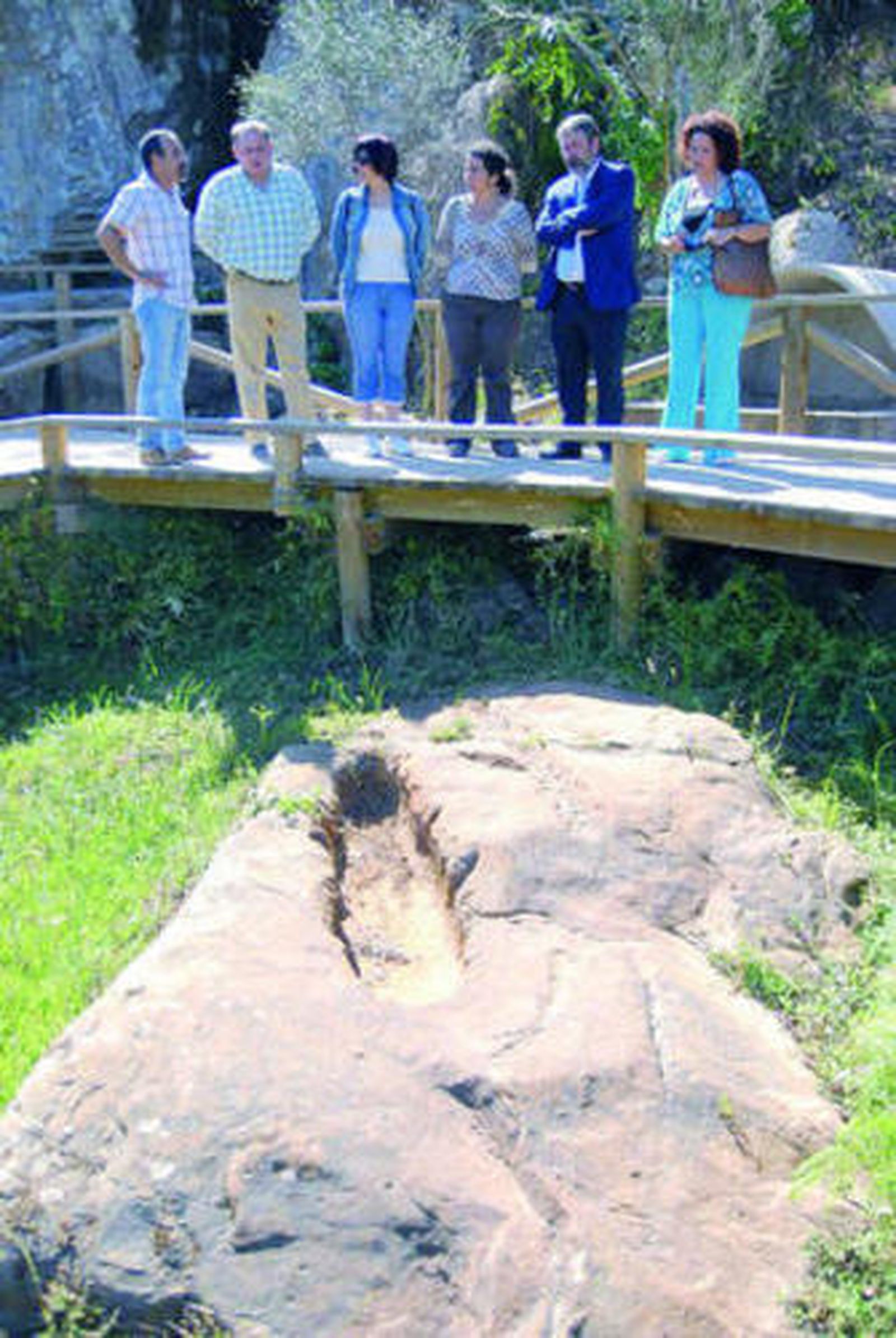 Las autoridades observan una de las tumbas antropomorfas desde una pasarela de madera.