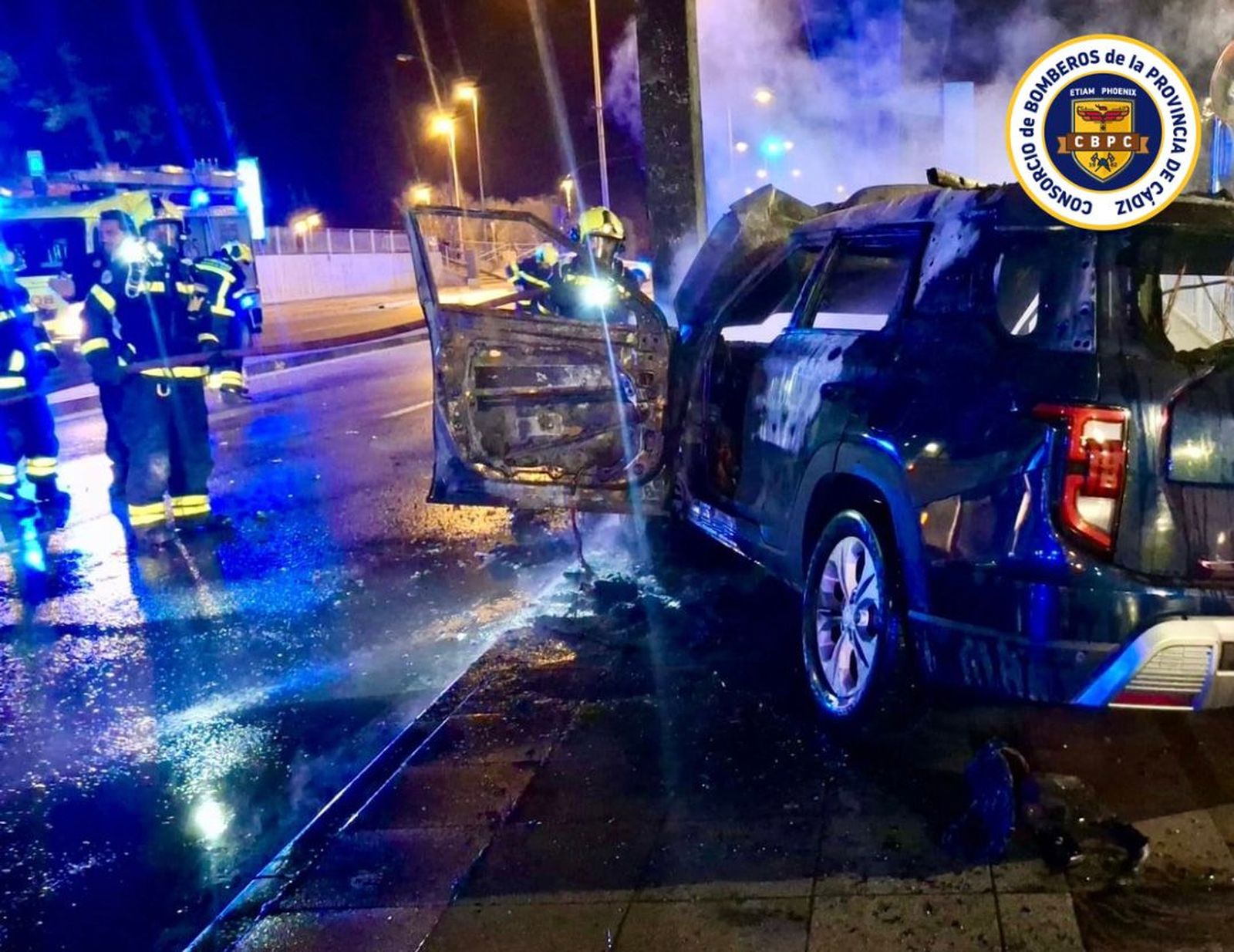 Bomberos apagan el fuego del coche accidentado junto al Hospital de Jerez.