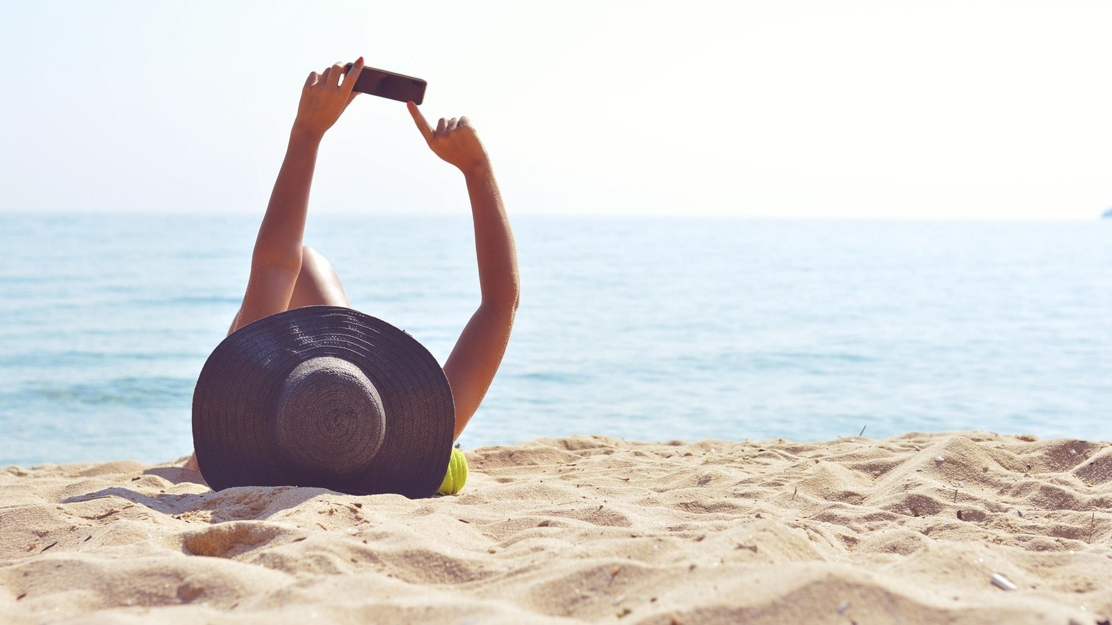 Imagen de archivo de una mujer haciéndose un selfie en la playa