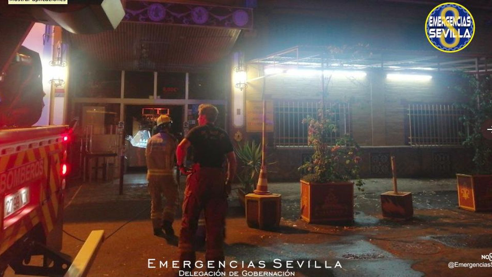 Los bomberos, a las puertas del primer establecimiento incendiado.