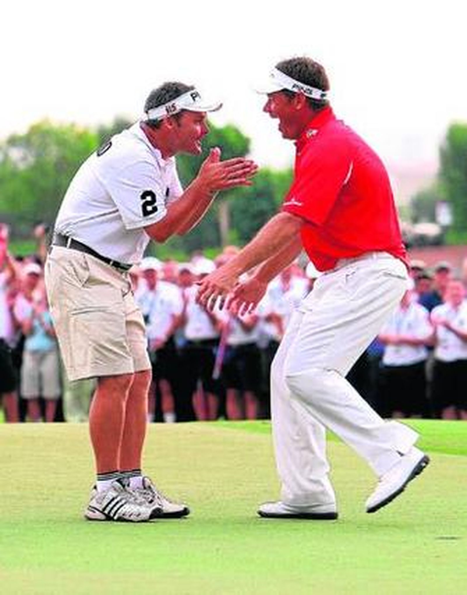 Westwood (d) celebra con su 'caddie' el triunfo en Dubai.