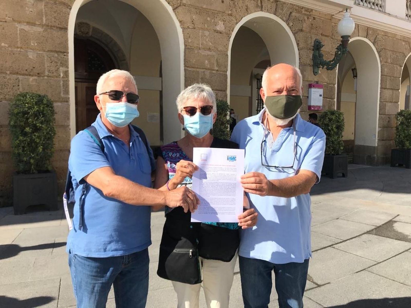 Miembros de la APDHA y el Comité Óscar Romero posan con el escrito que han remitido al Pleno municipal.