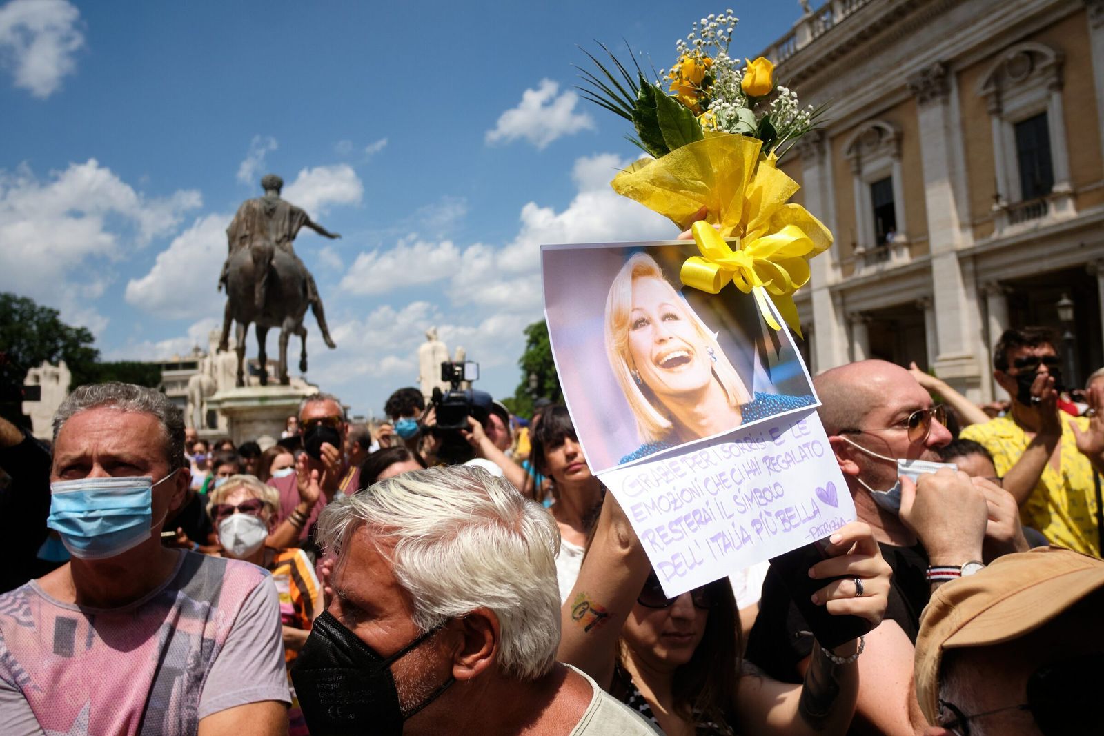 Italianos por las calles de Roma este viernes portando fotos de Raffaella Carrá y flores en su honor.