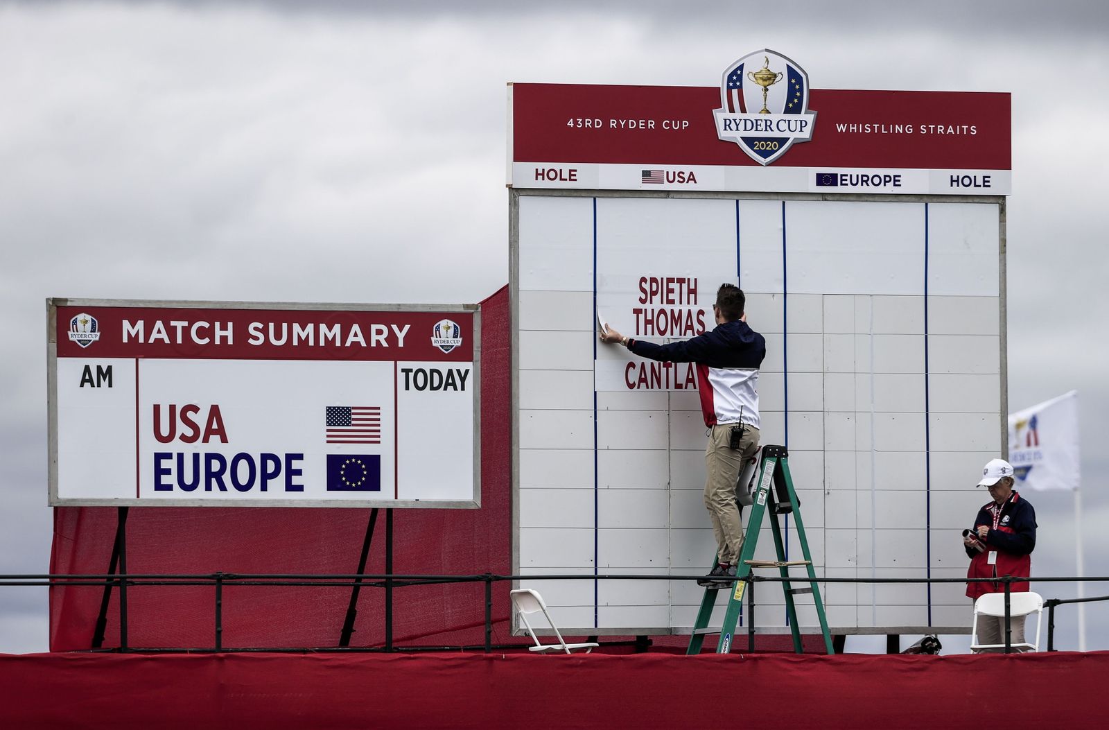 Un trabajador de la organización del torneo termina el cartel de la competición.