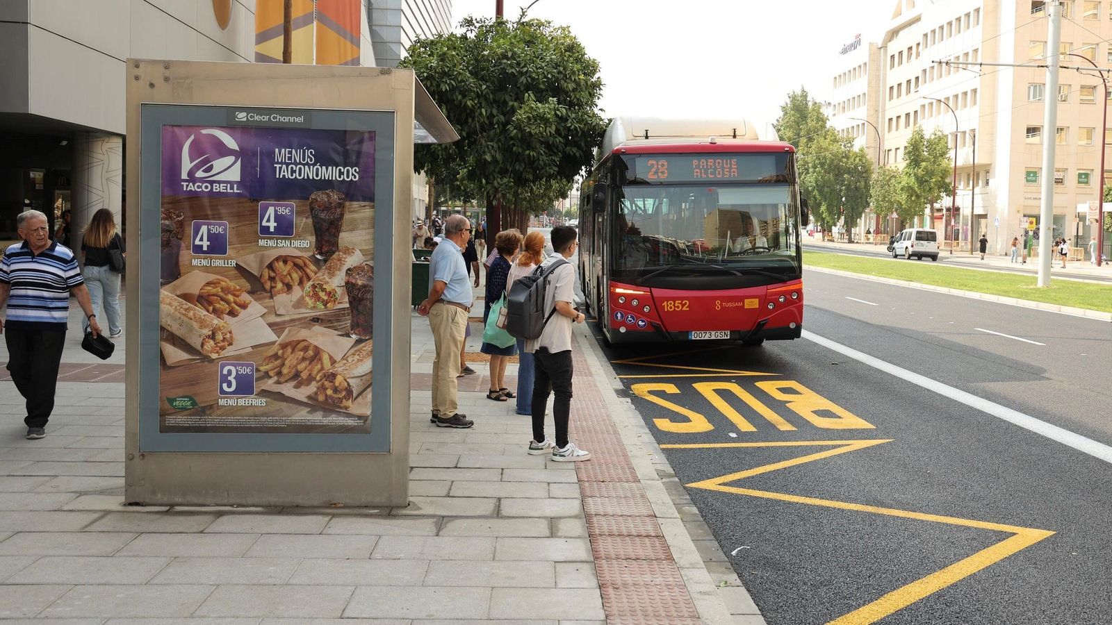 Varios transeúntes esperan el autobús en una de las paradas junto al centro comercial Nervión Plaza.