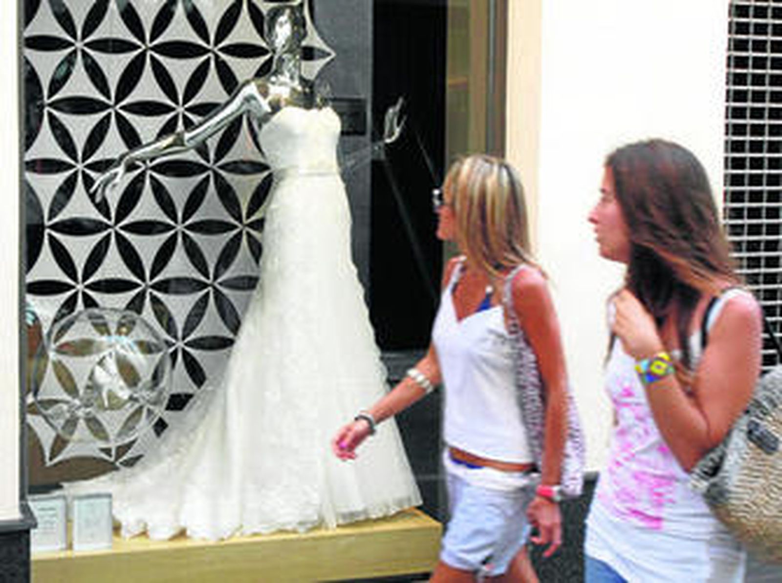 Dos jóvenes observan el traje de novia en un escaparate del centro de Cádiz.