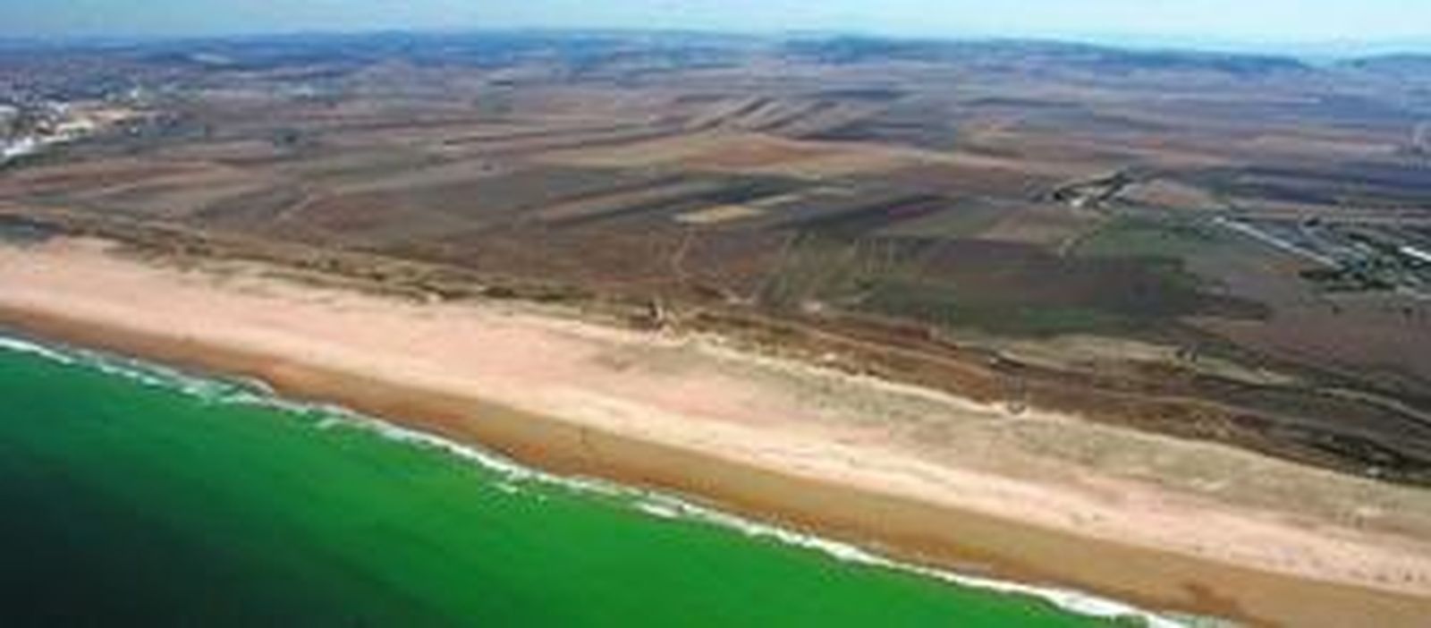 Panorámica del tramo de costa que une Conil y Vejer, con la playa de Castilnovo a la izquierda, la torre de El Palmar, y los terrenos de Riera Marsá a la derecha.
