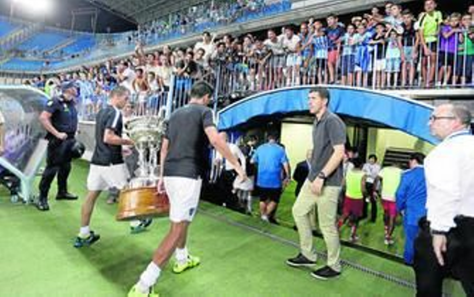 Javi Gracia observa cómo Duda y Recio portan el trofeo.