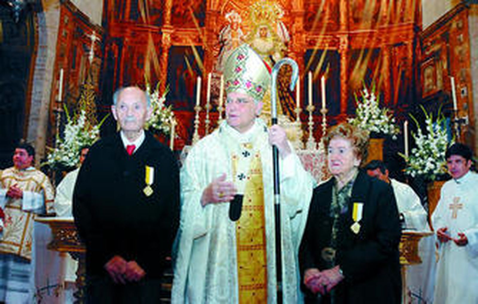Los condecorados Francisco Rodríguez y Ramona Santos posan junto al cardenal en el altar.
