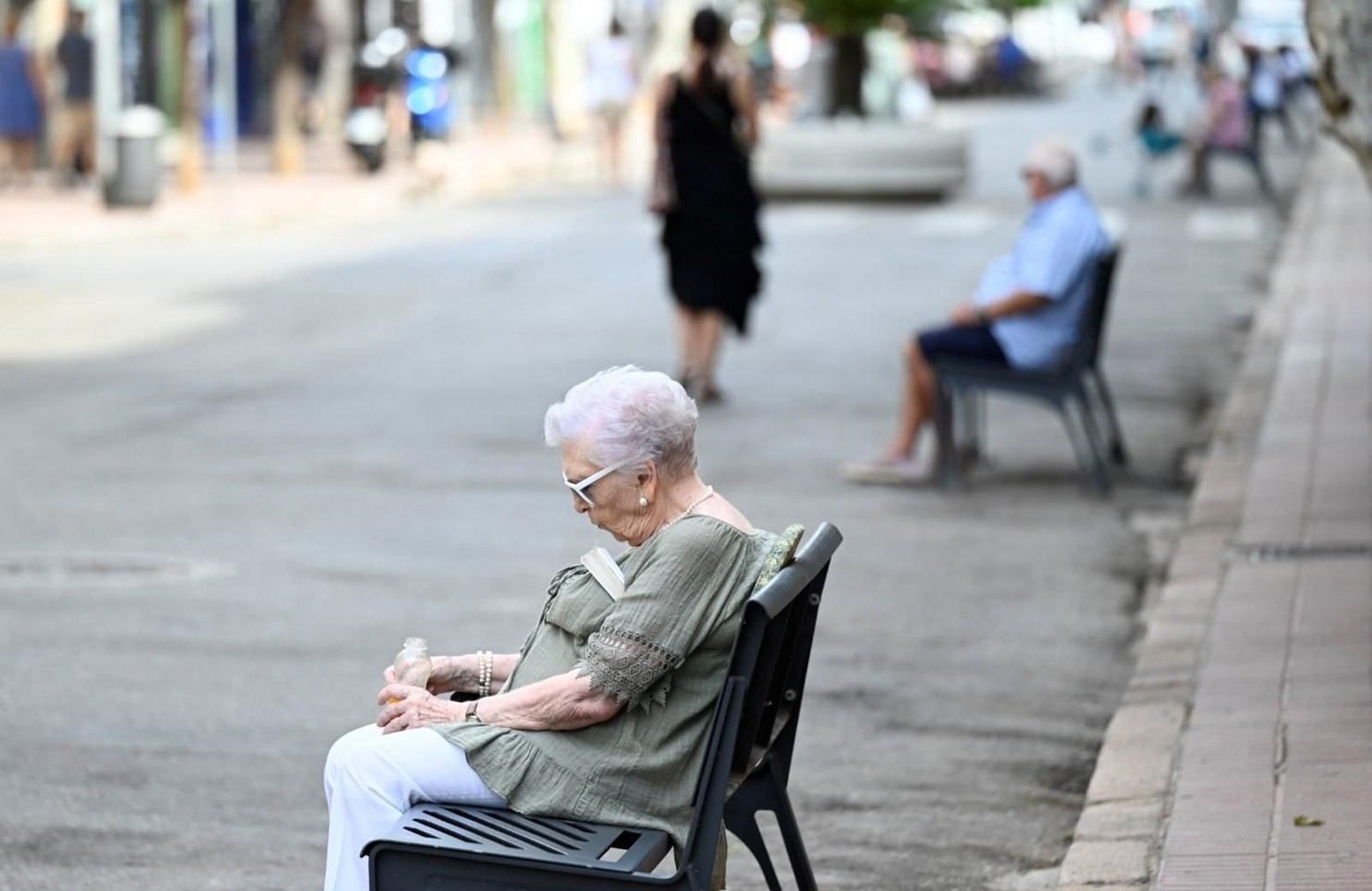 Una mujer mayor, sentada en un banco de la avenida de La Viñuela.