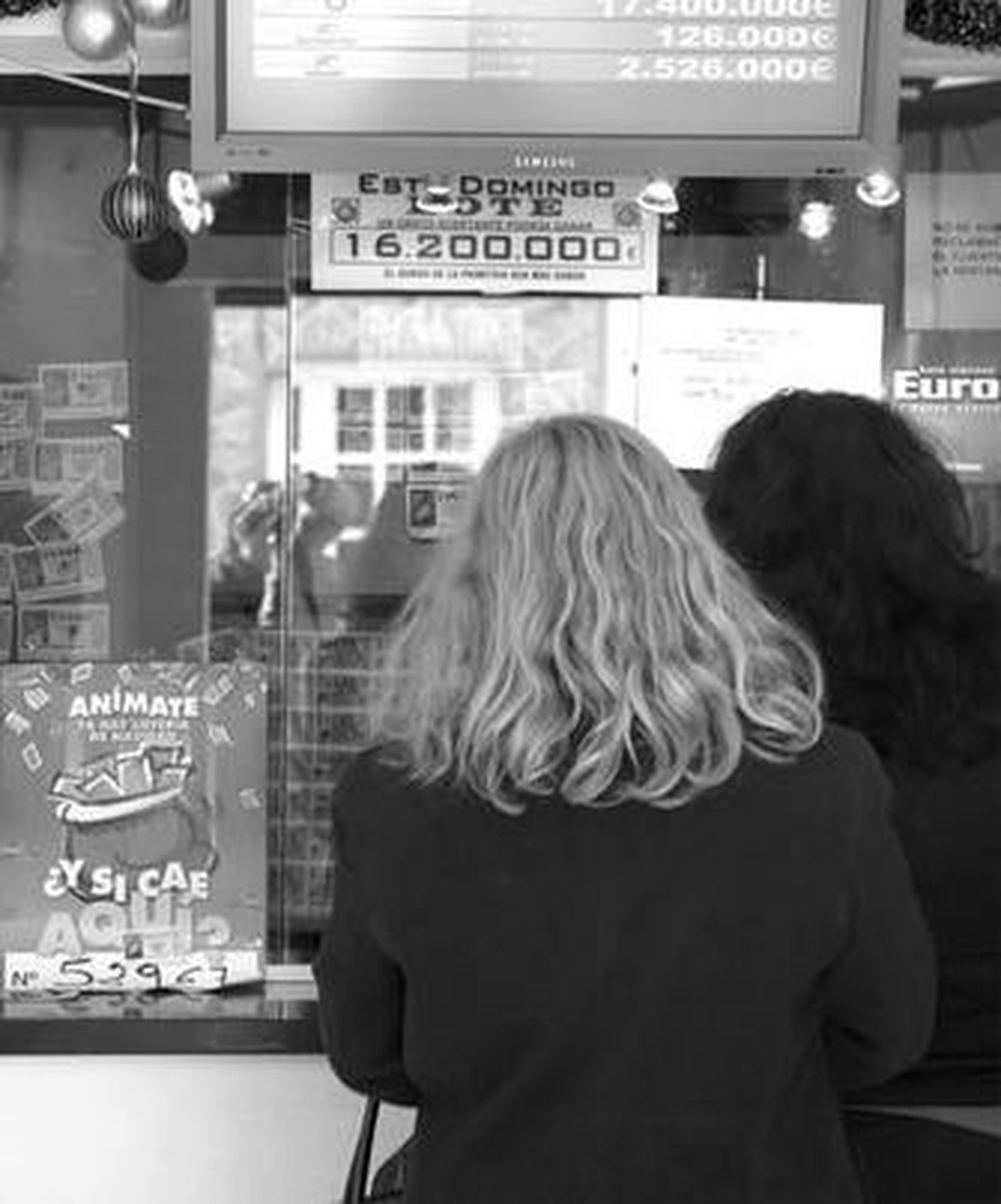 Dos mujeres guardan cola en una administración.