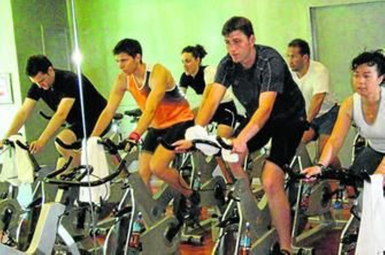 Un grupo de personas en una sala practican ciclo indoor.