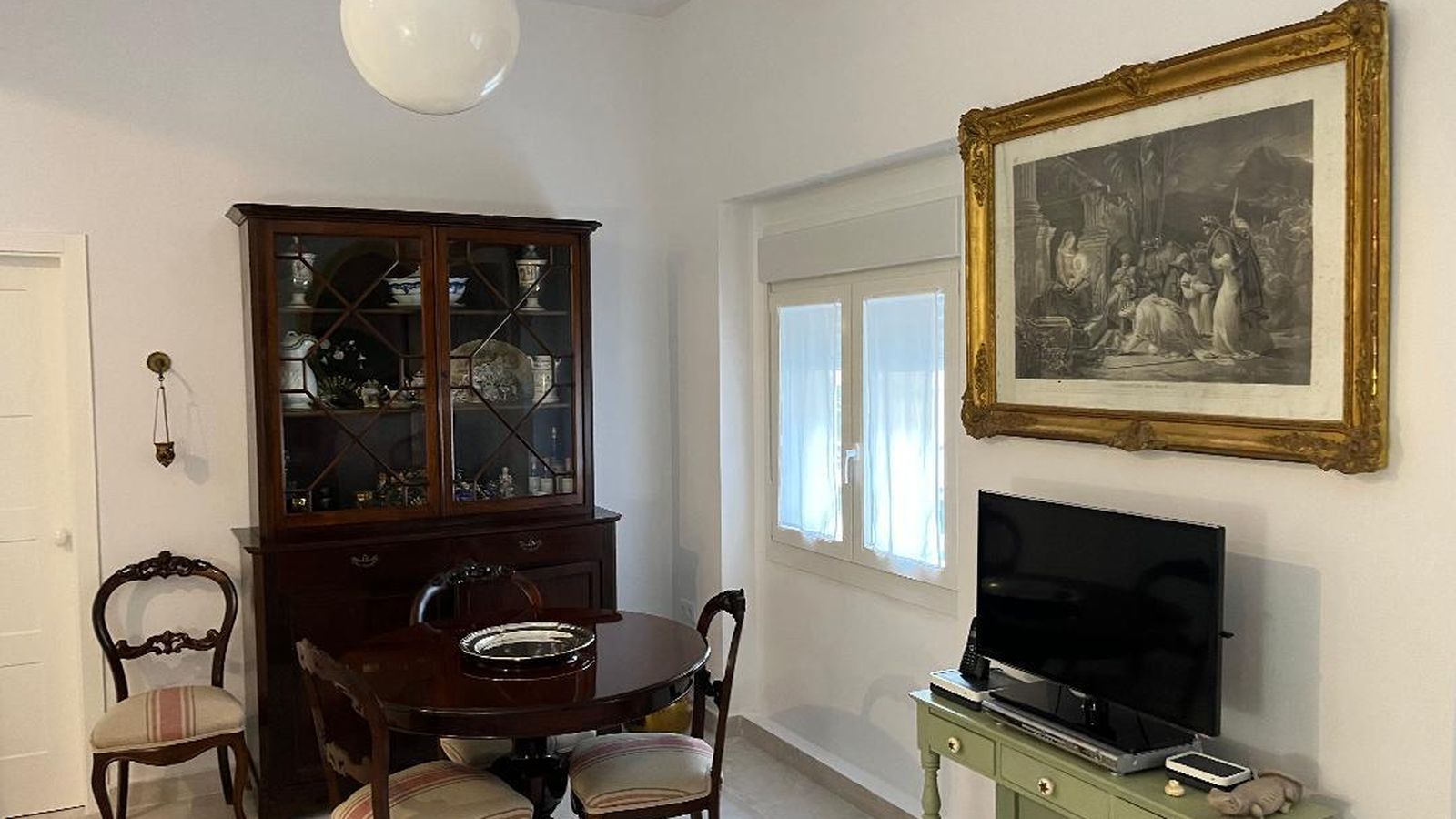 Mesa redonda de caoba con sillas isabelinas y vitrina de la misma época en el comedor.