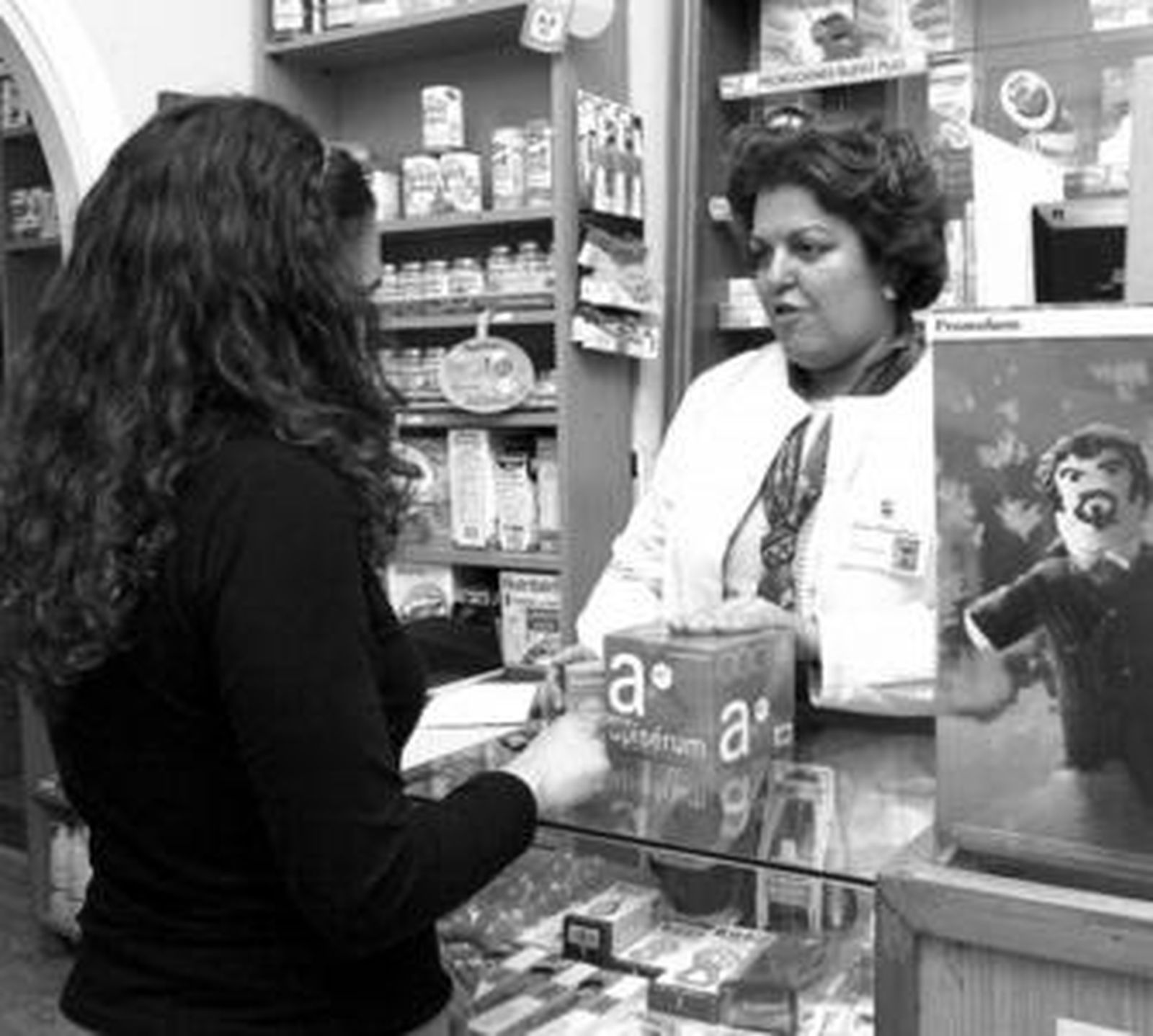 Una farmacéutica muestra un complejo vitamínico a una joven.