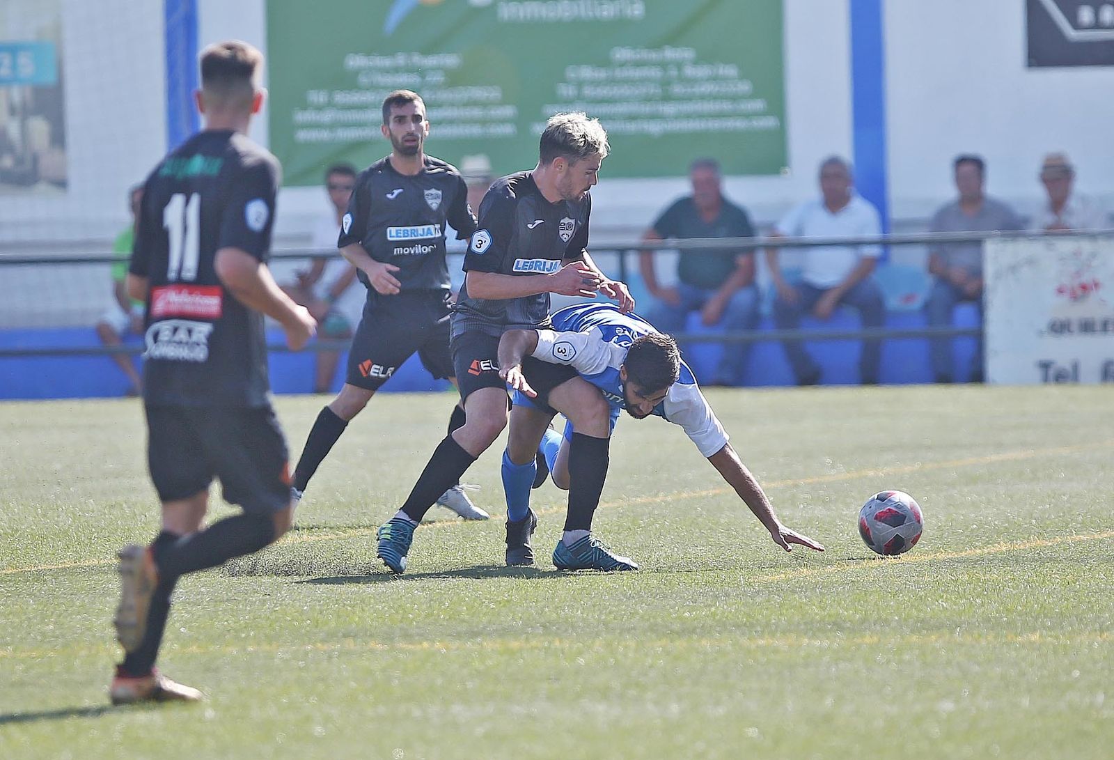 Sosa, centrocampista de la Lebrijana, derriba a un rival al intentar recuperar el balón.