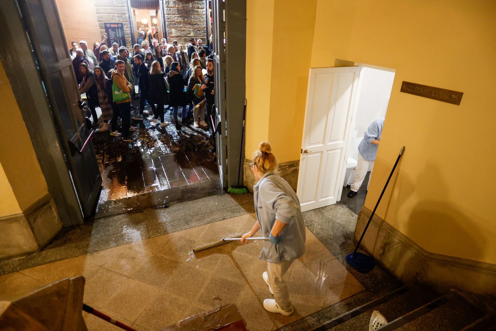 El personal de limpieza achicando el agua del cuarto de baño del Falla.