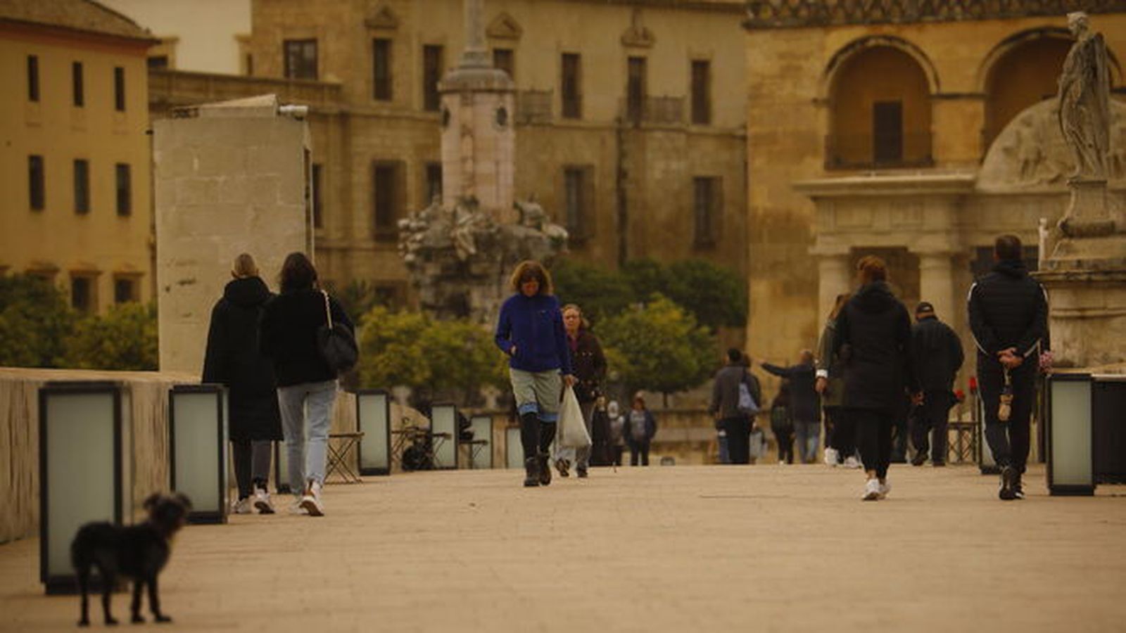 Varias personas en el puente romano de Córdoba, en otra jornada con calima.