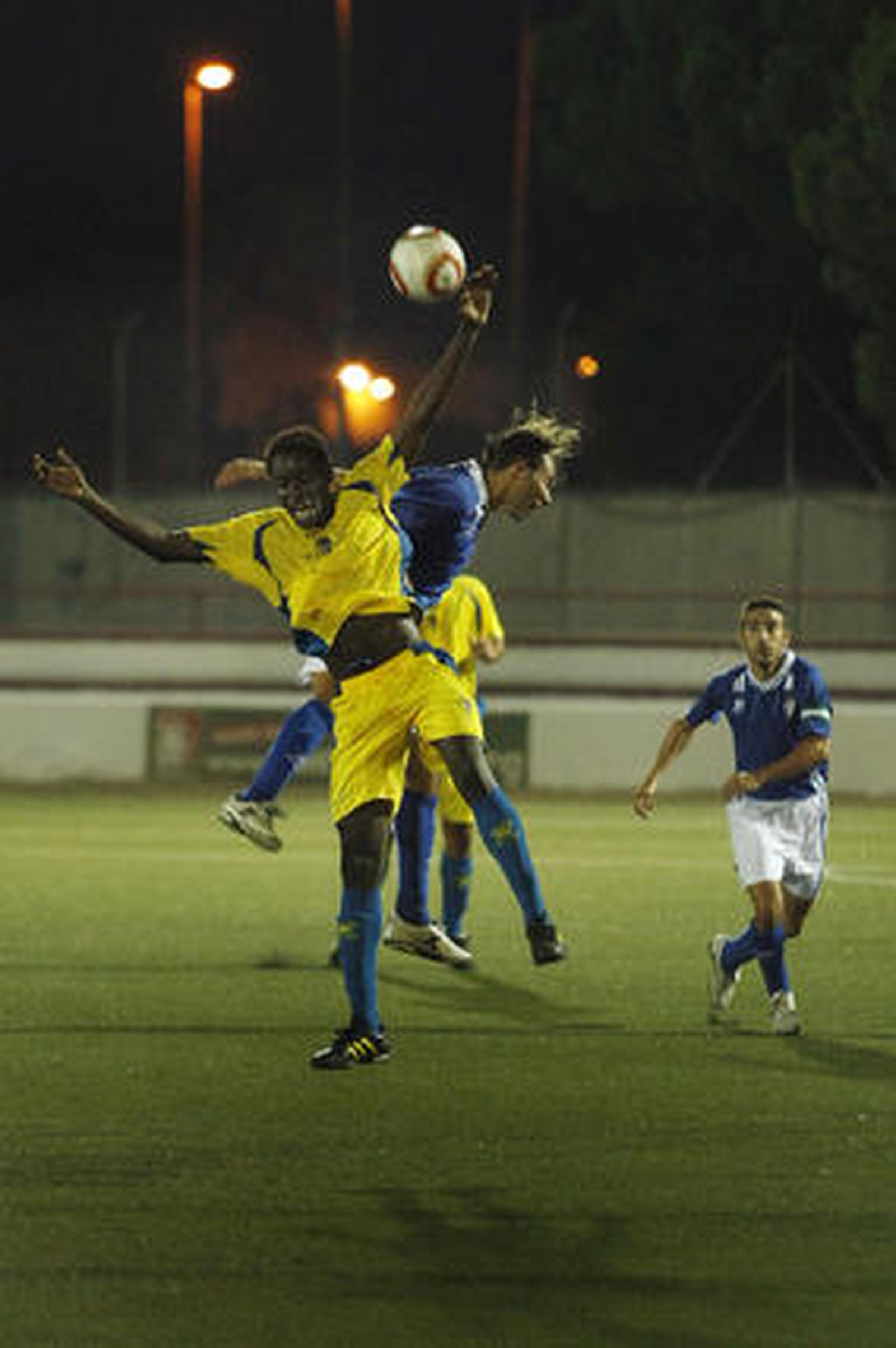 En el primer partido, el San Fernando sorprendió al Cádiz con un gol de Iván Guerrero, que en la imagen salta con el cadista Moke. 

Foto: Fito Carreto