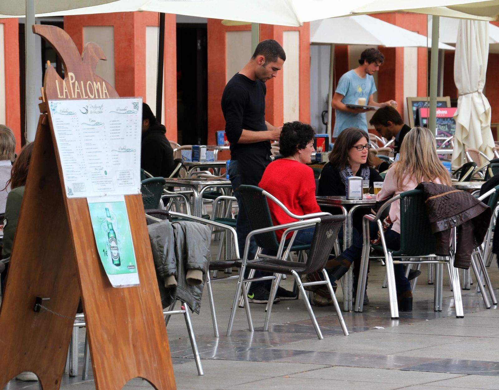 Un camarero atiende a unos comensales en la plaza de la Corredera.