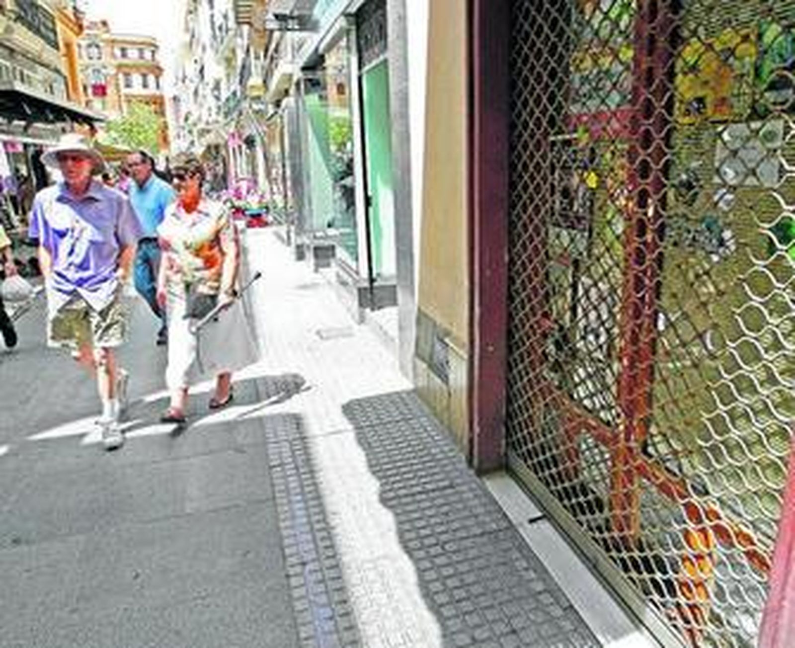 Turistas pasan por delante de una de las tiendas cerradas al mediodía de ayer en la calle Compañía.