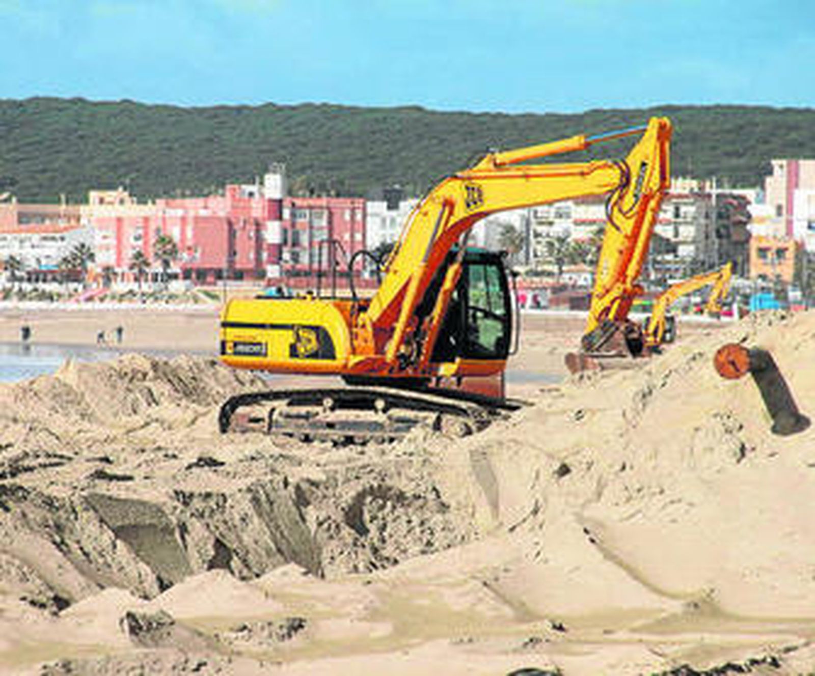 Una excavadora mueve la arena en la barbateña playa de El Carmen.