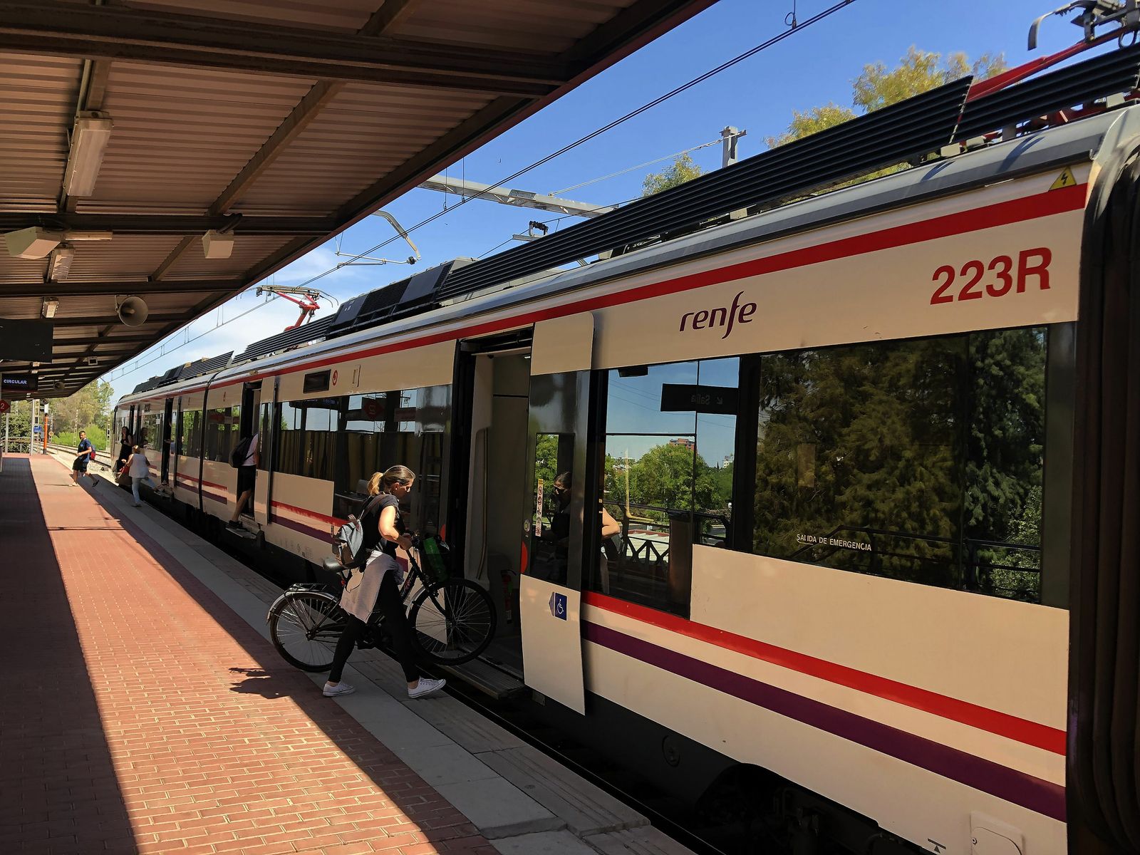 Una mujer entra con su bicicleta en un Cercanías en la estación del Palacio de Congresos.