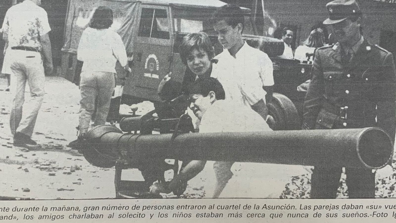Un soldado enseña a un niño las características de una pieza de artillería.