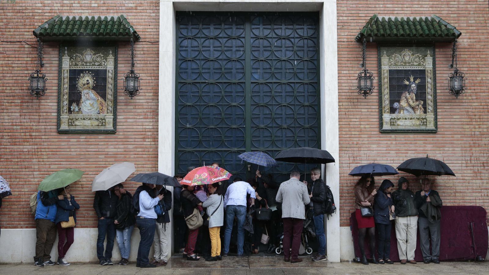 Un grupo de fieles se protege de la lluvia el Jueves Santo de 2019 en la capilla de las Cigarreras.