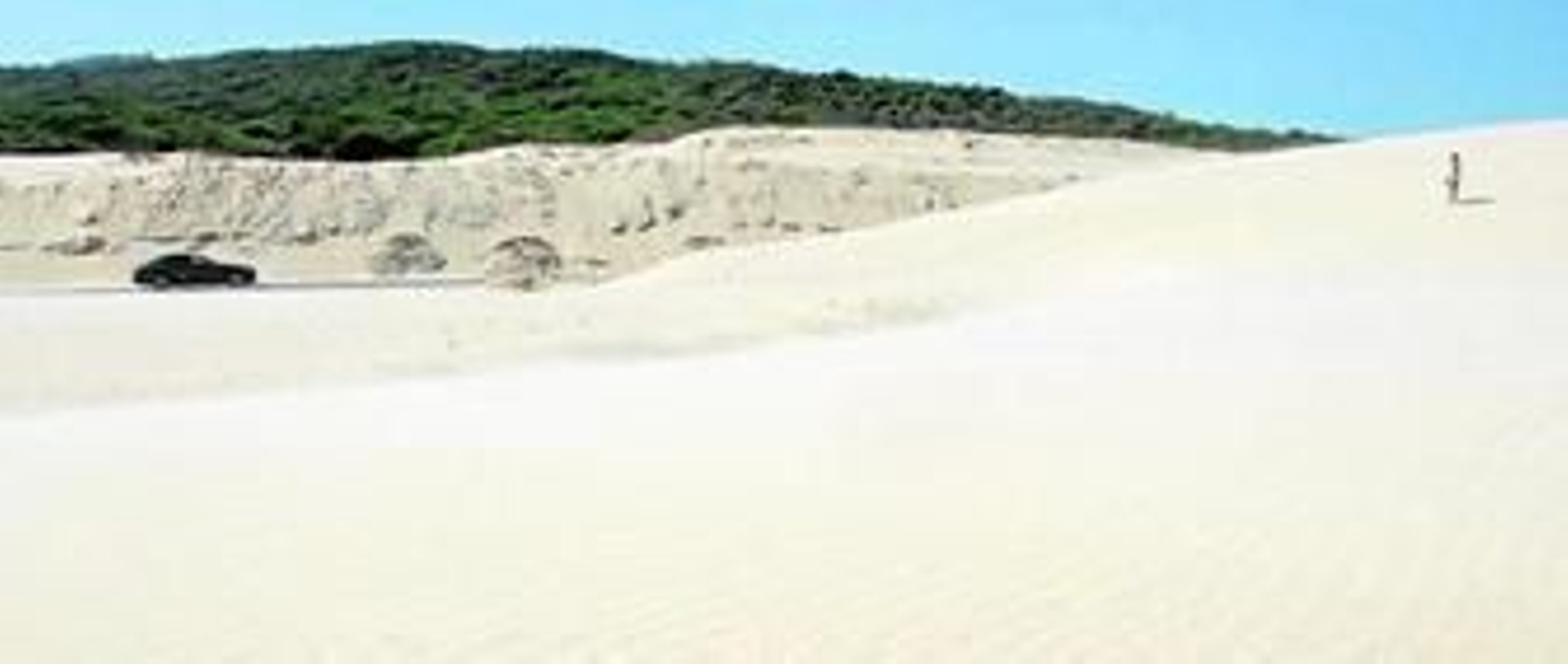 Una joven observa desde la duna a un vehículo circulando por la carretera A-2325, que conduce a Paloma, ayer.