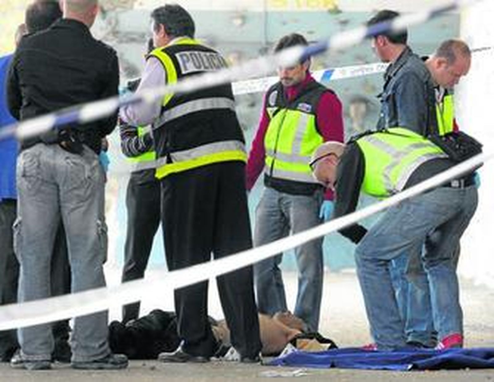 Los agentes de la Policía Científica y del grupo de Homicidios examinan el cadáver bajo el viaducto del Alamillo, frente al Estadio de la Cartuja.
