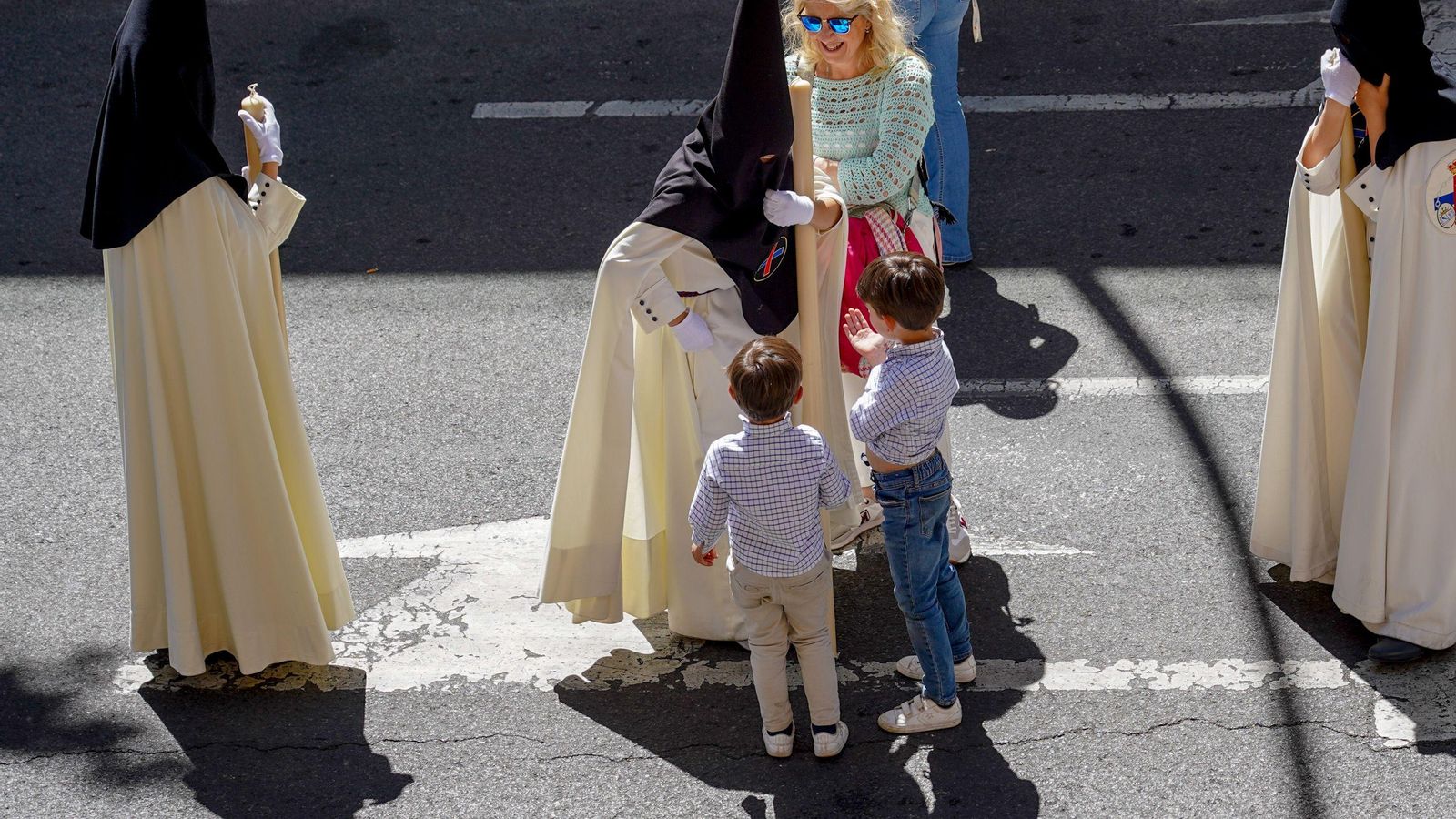 Dos niños piden caramelos a un nazareno del Polígono de San Pablo.