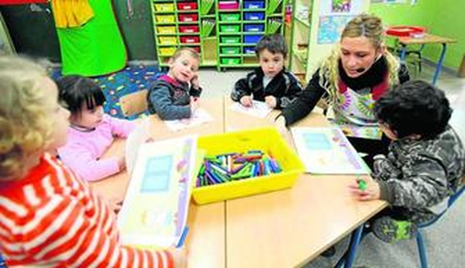 Una profesora trabajando, con micrófono para no perjudicar su garganta, en un aula de Infantil.