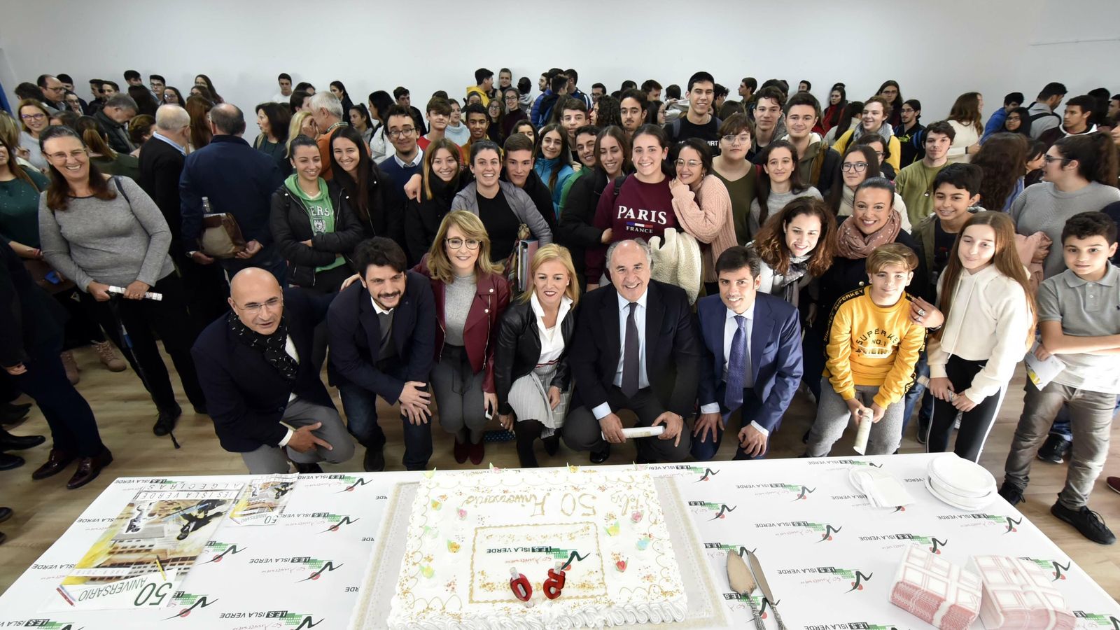 Foto de familia de la celebración con la tarta de los 50 años en primer término.