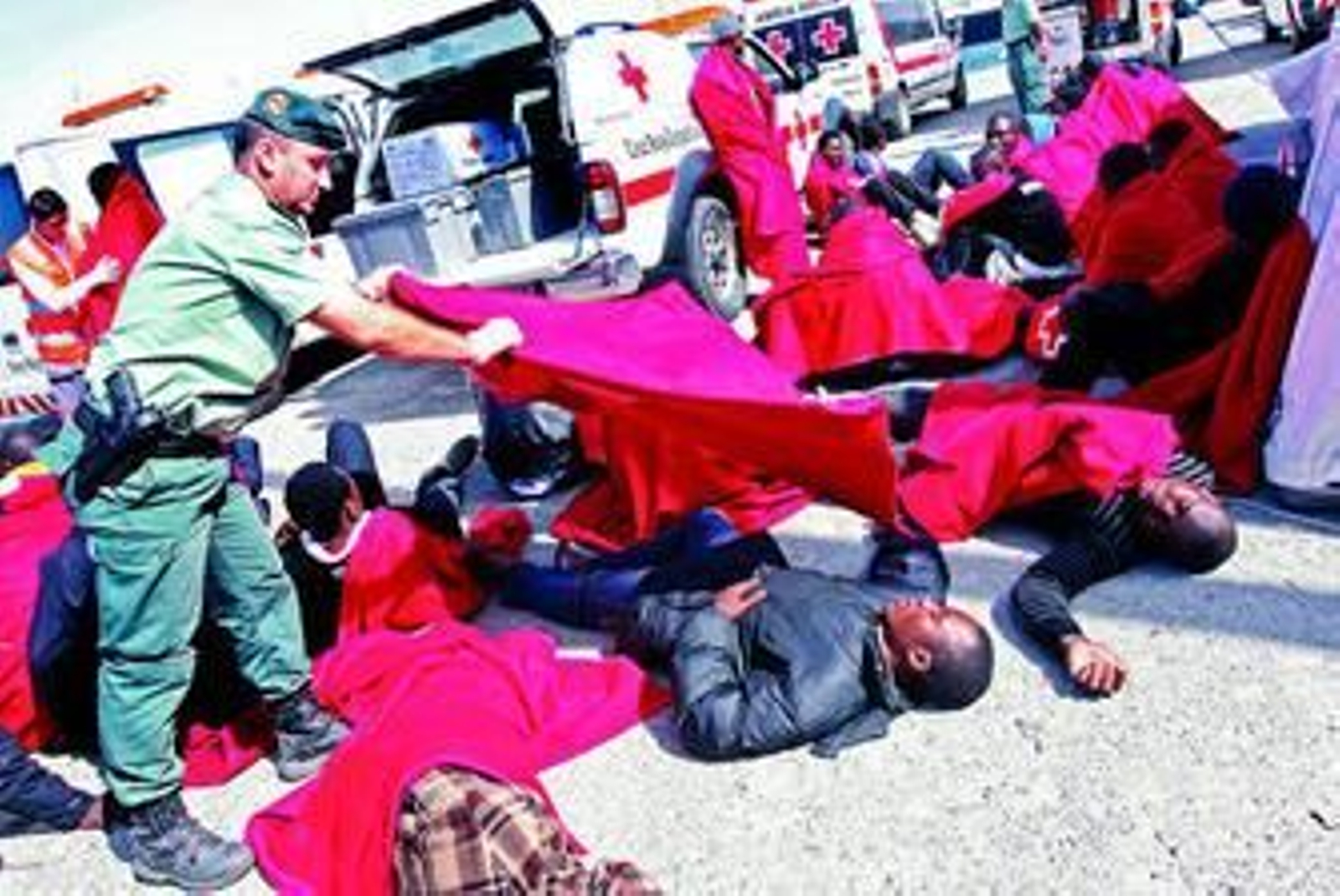 Un guardia civil presta servicio ayer en Tarifa a uno de los inmigrantes que llegaron en patera.