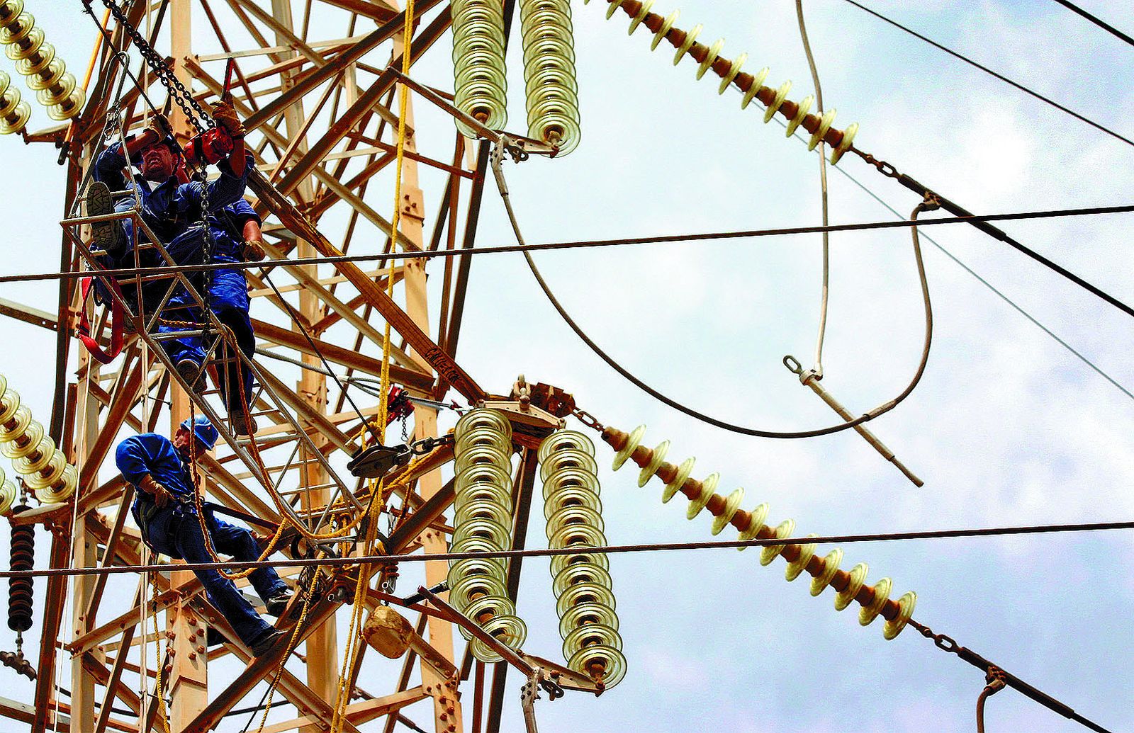 Operarios trabajan en una red eléctrica de alta tensión.