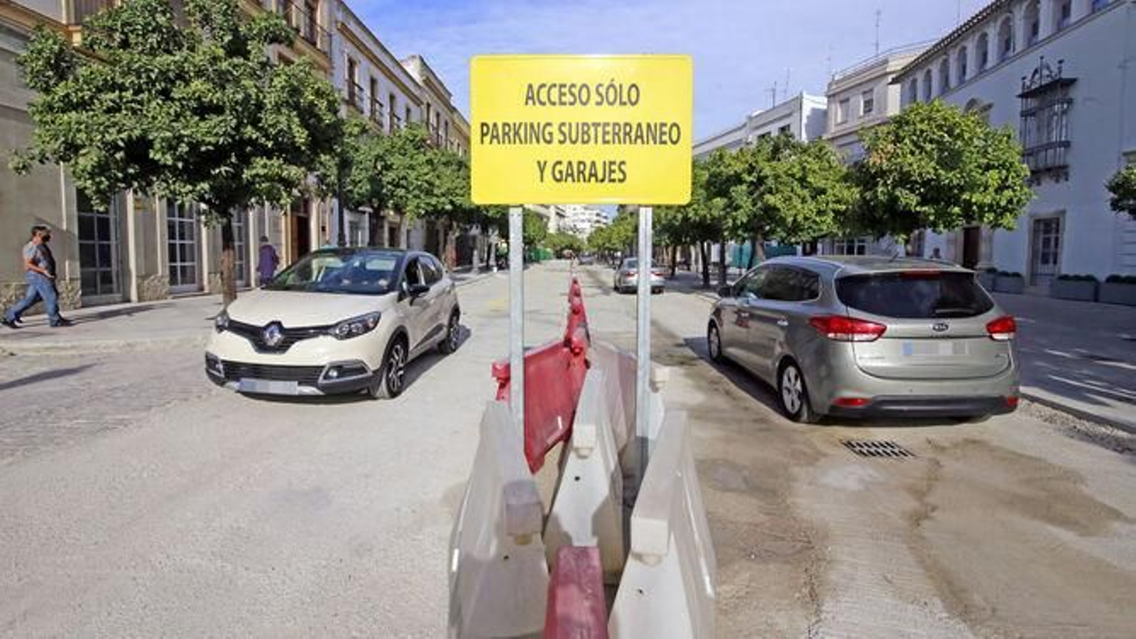 Una pareja cruza la calle Corredera tras su reapertura provisional al tráfico sin asfalto.