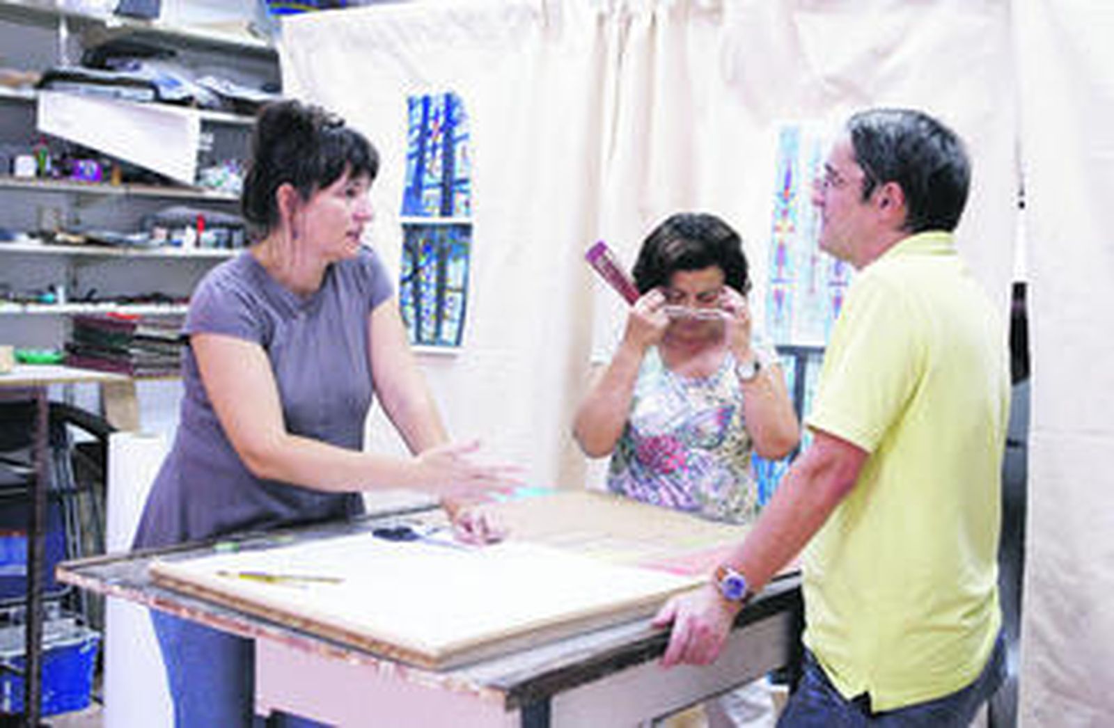 Victoria Márquez comparte su técnica del vidrio con Juan Melgar, dentista, en presencia de Dolores López, administrativa.