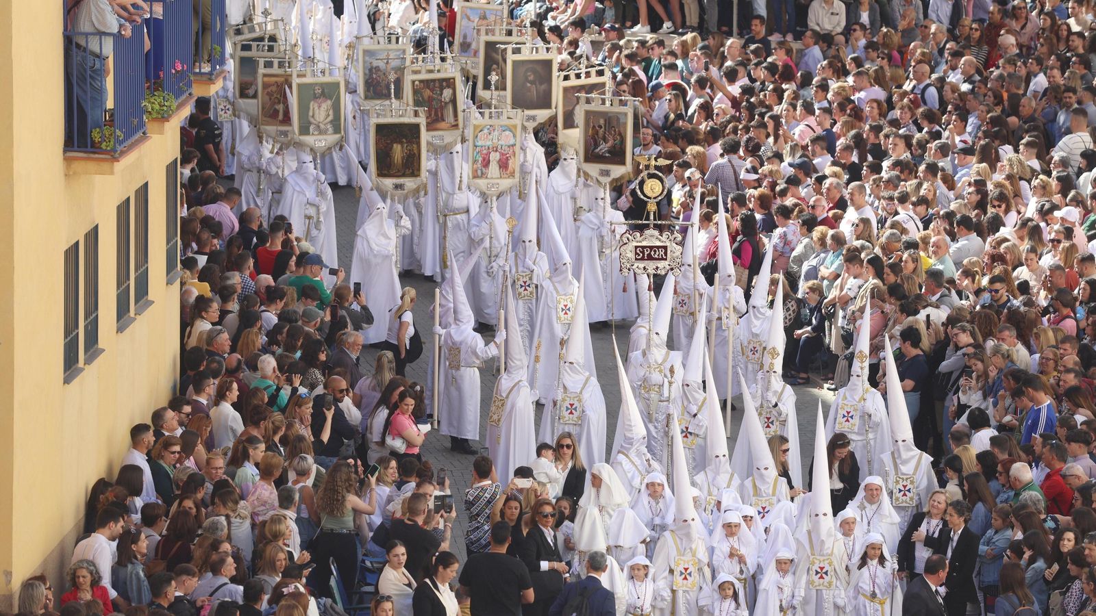 Los capirotes blancos avanzan entre la multitud de público congregado en La Trinidad.