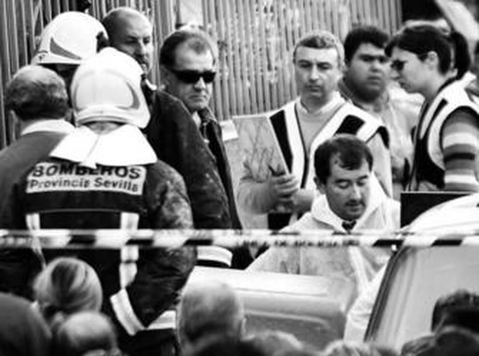 Bomberos y policías contemplan la salida de uno de los féretros, el pasado domingo en Écija.