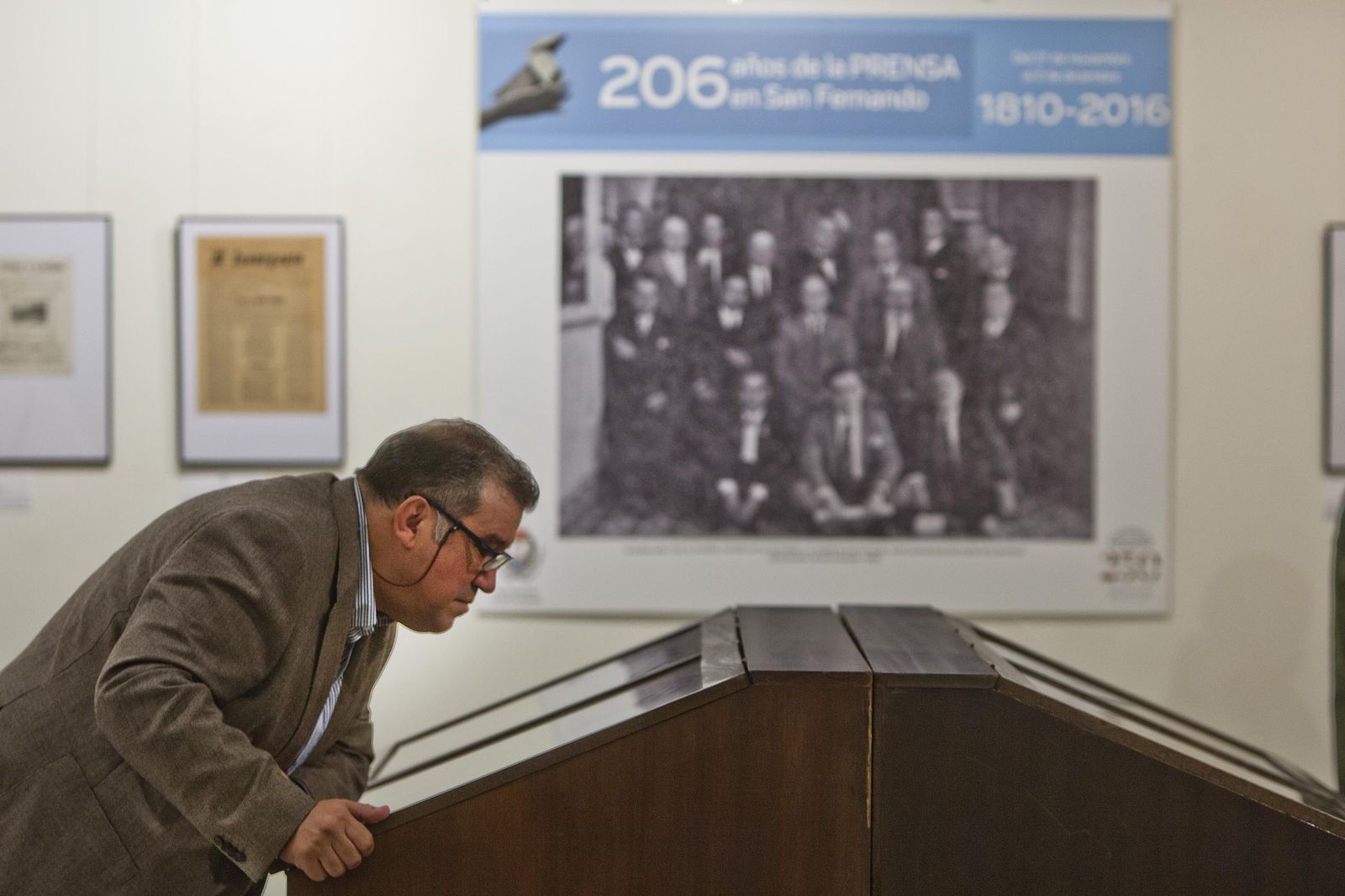 Un isleño se inclina ante la vitrina central de la exposición para apreciar el contenido expuesto.