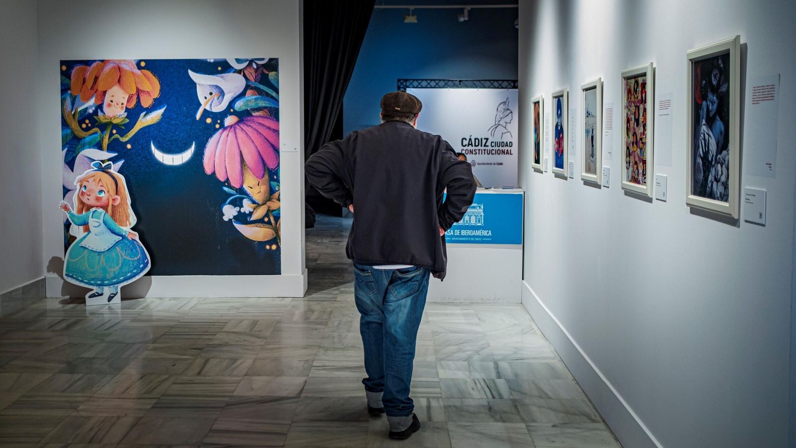 La ilustración de ‘Alicia’, la de mayor tamaño de la exposición, junto a una figura del popular personaje infantil.