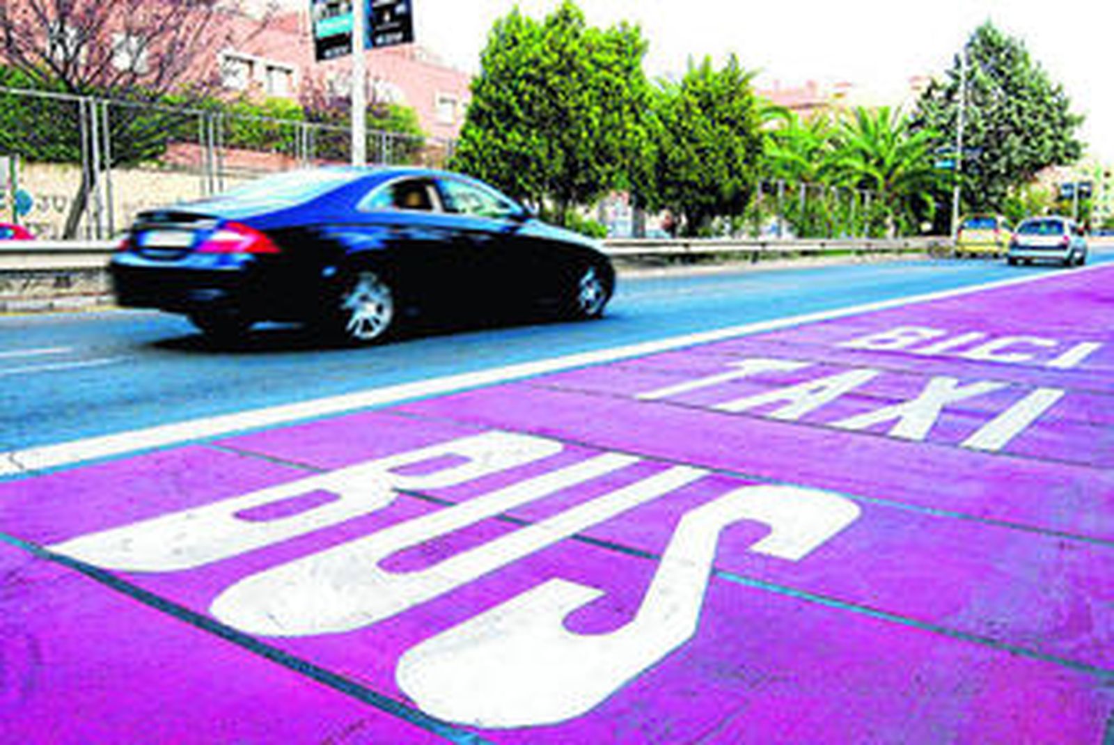 Un coche pasa junto a un carril bus.