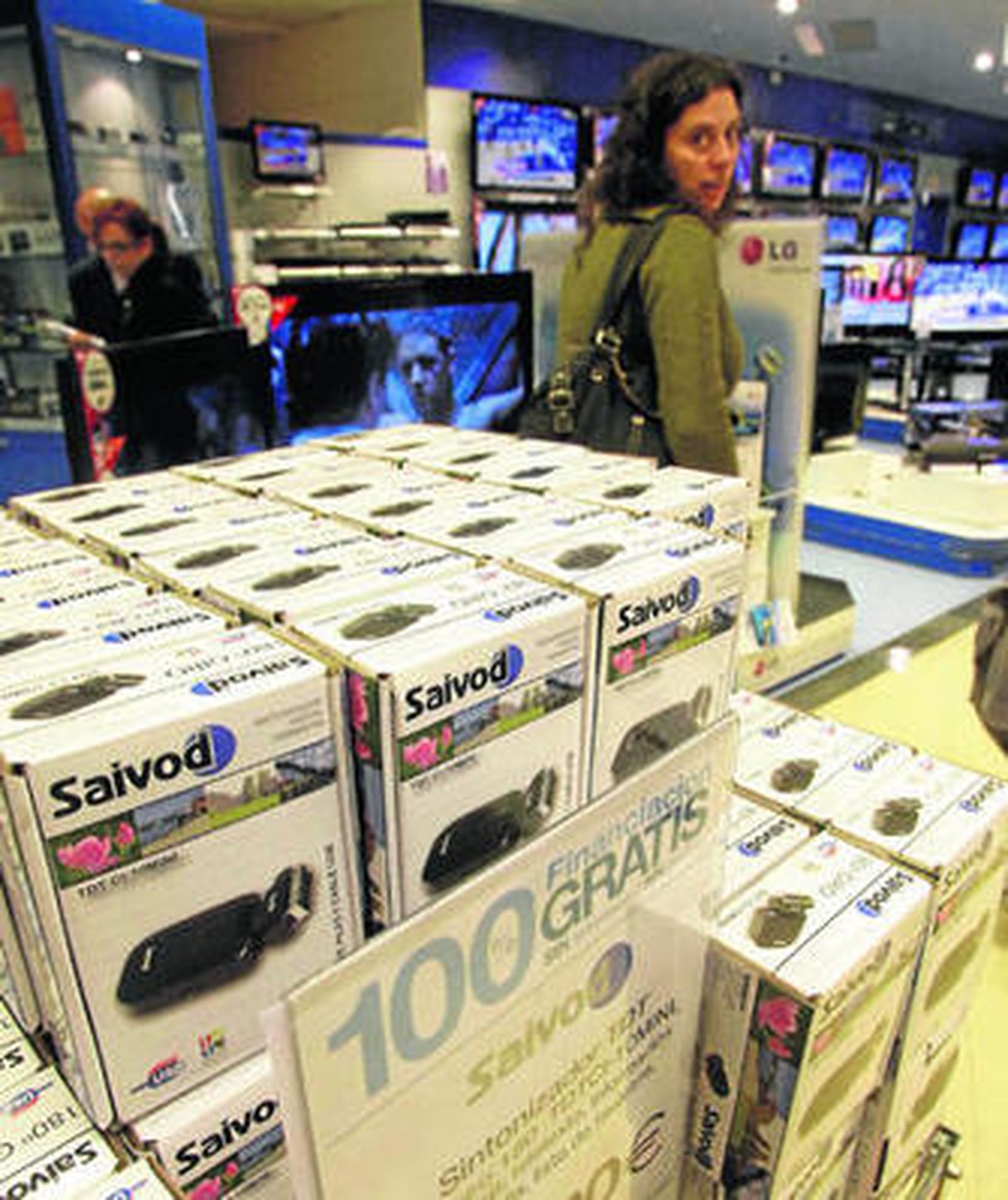 Sintonizadores de TDT a la venta en un centro comercial y, al fondo, modernas televisiones con receptor incorporado.